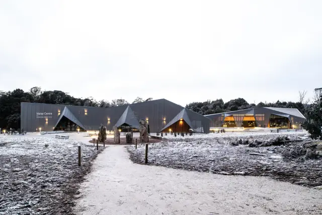 The Cradle Mountain Visitor Centre’s angular exterior in a snowy landscape.